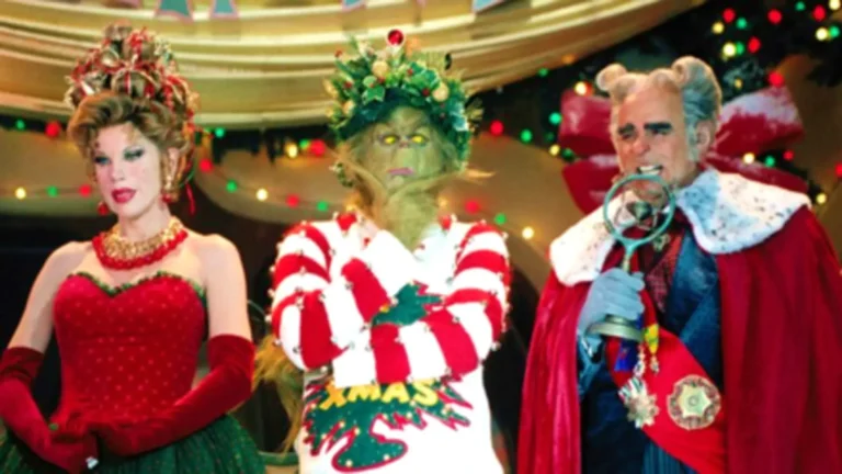 Jim Carrey como El Grinch con expresión burlona y fondo navideño en Villa Quién